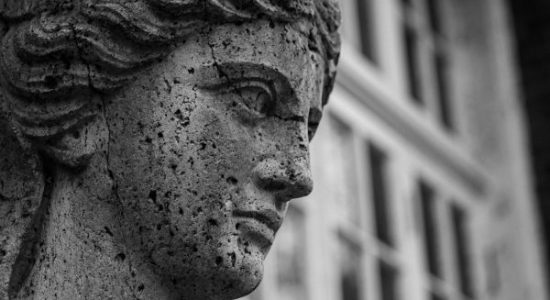 A detailed black and white image of an ancient stone statue with a classical design.